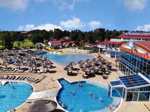 Słoneczny aquapark nad morzem z basenami, zjeżdżalniami i leżakami pod parasolami.